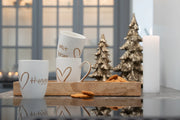 Hvidt keramisk Hygge-krus med guldfarvet tekst og hjerte – elegant kaffekrus i nordisk design fra BiMe.dk.